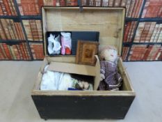 A vintage wooden metal-studded trunk containing a collection of textiles, dolls, leather Gladstone