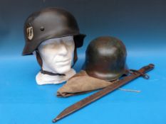 Two German helmets, one with SS and swastika emblems, together with a helmet cover with Nazi emblem