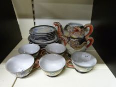 A decorative Japanese tea set, two teapots, five cups and saucers, with dragon overlaid decoration