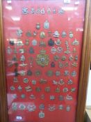 A framed display of cap and other badges to include Tank Corps, Welsh Regiments etc