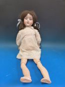A Schoenau & Hoffmeister bisque headed doll with open mouth and weighted brown eyes,