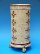 A late 19th/20thC Mettlach cylinder vase with enamelled decoration, raised on thee scrolling feet,
