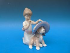 A Lladro figure of a girl with a dog wearing a hat 