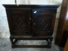 A small hall cabinet/utility cupboard on legs with two carved doors (W64, D22,
