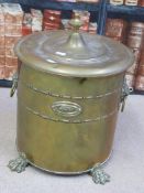 A circular brass coal bin raised on lions paw feet