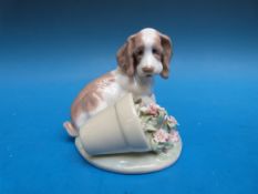 A Lladro figurine of a dog knocking over a flowerpot 