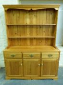 A pine dresser with plate rack to top and three drawers and three cupboards to base (W137, D44,