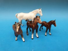 A Beswick standing dappled grey horse together with three brown foals
