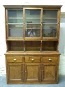 A large pine dresser, the top section having sliding glazed doors,