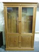 A pine display cabinet with glazed upper section and cupboard below (W127, D38,