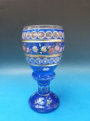 A Bohemian double overlaid cut glass goblet with floral enamel decoration and gilt banding to the