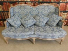 A French limed oak six legged sofa with brocade upholstery