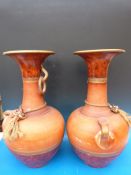 A pair of large terracotta urns with loop handles and rope adornments (60cm high)