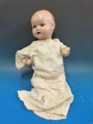 A resin headed doll with open mouth, fixed blue eyes and moulded hair,