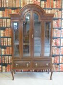 A late 19thC or early 20thC mahogany glazed cabinet with domed pediment and bevelled glass (W125,