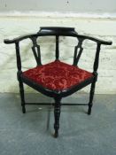 An ebonised corner chair with turned supports united by further turned x shaped stretcher