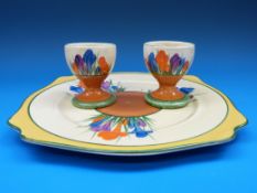 A Clarice Cliff pair of egg cups and a cake plate,