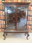 A late 19th or early 20th century display cabinet with carved and moulded decoration and astragal