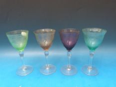 A set of four coloured glasses with etched decoration depicting figured scenes, 16cm tall.