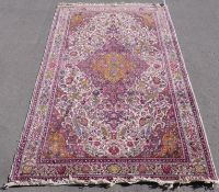 A Persian wool rug with purple and green birds amongst foliage on beige ground