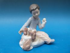 A Lladro figurine of boy with puppies 