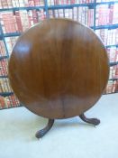 A 19thC mahogany tilt top circular breakfast table raised on a scrolling tripod base and a ceramic