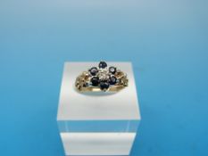 A 9ct gold ring set with a central diamond surrounded by sapphires in a flower cluster