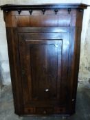 A 19thC oak and mahogany hanging corner cupboard with single drawer flanked by two dummy drawers