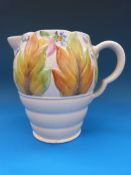 A Clarice Cliff jug decorated with flowers and foliage