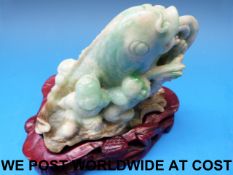 A Chinese jadeite carved model of a carp being wrestled by three boys,