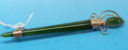 A jadeite brooch in the form of a sword in scabbard with yellow metal mount marked 8ct