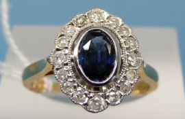 An 18ct gold ring set with a central oval sapphire surrounded by diamonds (size N)