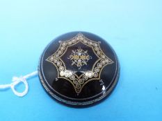 A circular tortoiseshell brooch inlaid with gold and silver