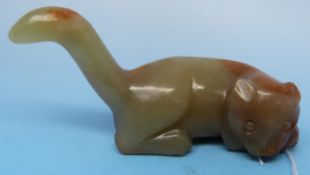 A Chinese jade carving of a recumbent cat with tail raised and russet inclusions (7.