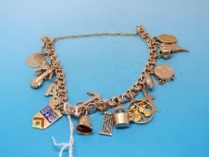A yellow metal charm bracelet with 17 yellow metal/9ct gold charms to include a poodle, anchor,