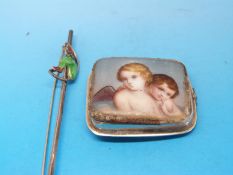 A silver brooch set with an enamel figure and a small ceramic plaque decorated with two cherubs set