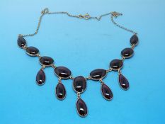 A 9ct gold necklace set with fourteen garnet cabochons