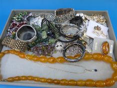 A tray of largely costume jewellery including a silver and amber brooch,