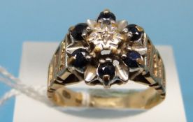 A 9ct gold ring set with a diamond surrounded by sapphires (size N)
