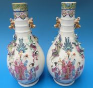 A pair of 19thC Chinese vases with famille rose figural decoration and applied Foo Dog handles,