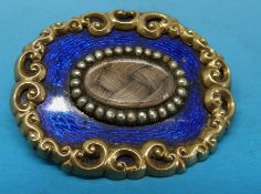A Victorian gold mourning brooch with an oval hair compartment to the centre surrounded by a row of