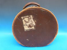A vintage circular leather mounted hat box with lined interior and pocket to lid