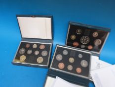Three UK proof coin collections by the British Royal Mint in deluxe cases,