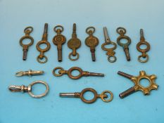 A small tin containing eleven various sized pocket watch keys and two yellow metal Albert clips