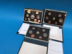 Three UK proof coin collections by the British Royal Mint in deluxe cases, comprising 1986,