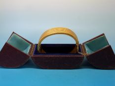 A yellow metal bangle with engraved banded rope design in bands,