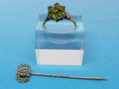 A 9ct gold ring set with peridots in a flower cluster and a yellow metal stick pin set with