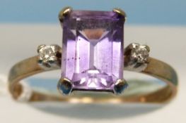 A 9ct gold ring set with an emerald cut amethyst with a diamond to each shoulder (size O)