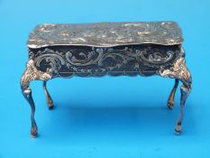 A hallmarked silver repoussé miniature table opening to form a trinket box, raised on cabriole legs,