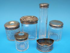 Five glass and hallmarked silver pots comprising four circular and one oval shaped with an embossed